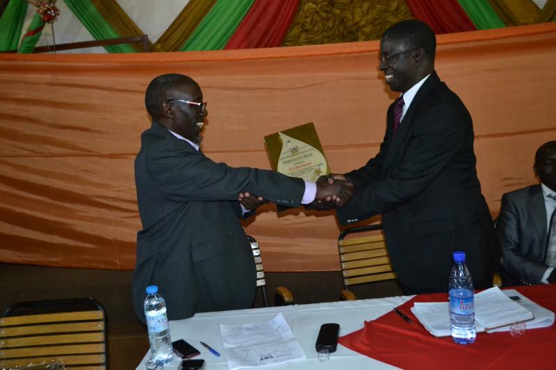 Prof. Kirumira hands a plaque to Prof. Kiyimba in appreciation of his service