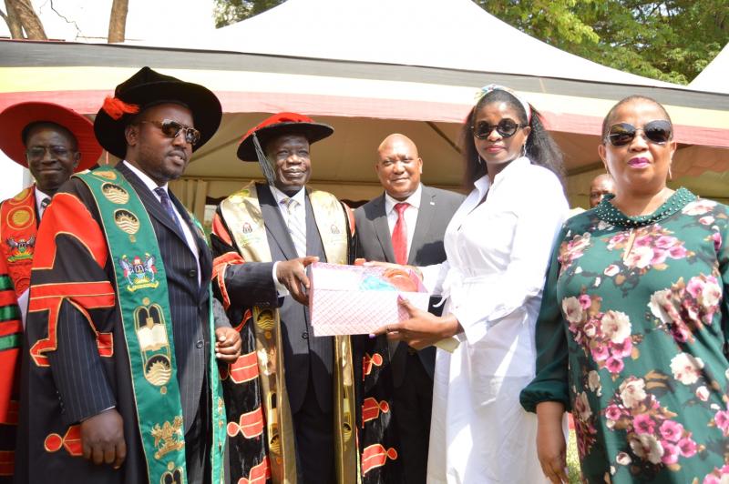 The Chairperson Makerere University Council, Eng. Dr. Charles Wana-Etyem presents a gift to Ms Gandhi Baai