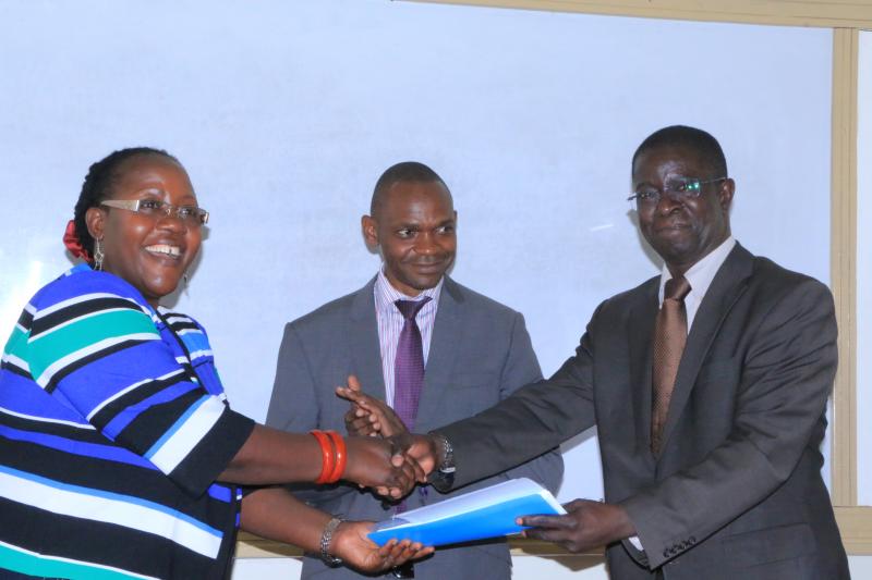 Prof. Kirumira hands over to Dr Ahikire. At the centre is Dr Kakumba, DVC, Academic Affairs