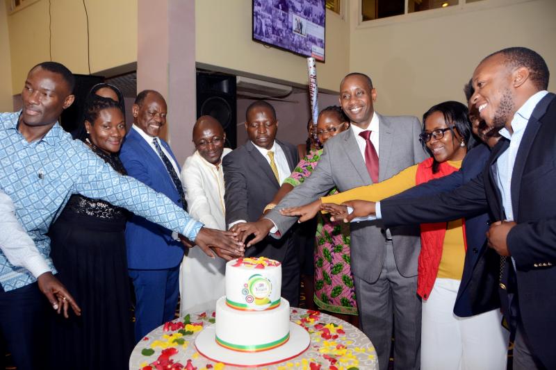 Some of the pioneer students cutting cake with Minister Bahati and Makerere University officials