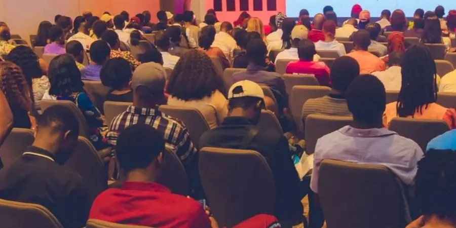 Delegates seated in a packed conference hall, listening to a presentation