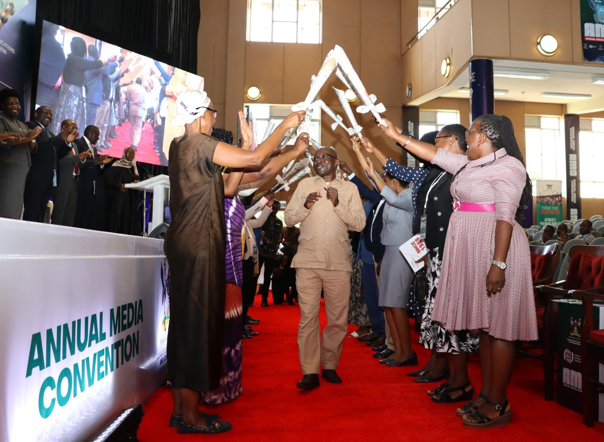 Dr. Adolf Mbaine walks in between staff crowned by newspapers in honor of his service