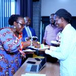 Dr Susan Kiguli Serves Cake to the College Principal Prof. Josephine Ahikire